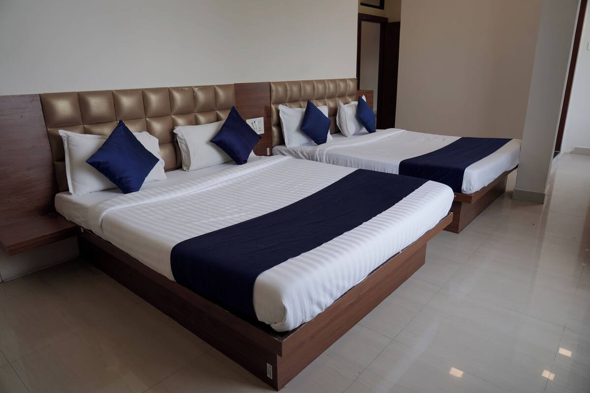 A hotel room with two beds, each with a wooden headboard and white bedding.