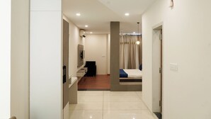 A modern hotel room with a bed, a desk, and a chair. There is a staircase leading to another level. - Hotel Suryodaya (Ujjain)