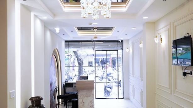 A spacious hallway with a marble floor, a large chandelier, and a view of the street through a glass door. - Hotel Suryodaya (Ujjain)