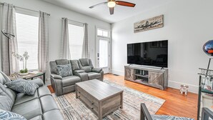 A spacious living room with a leather sofa, a wooden coffee table, a TV, and a ceiling fan. - 4 Mi to Kentucky Derby: Home w/ Private Yard (Louisville)