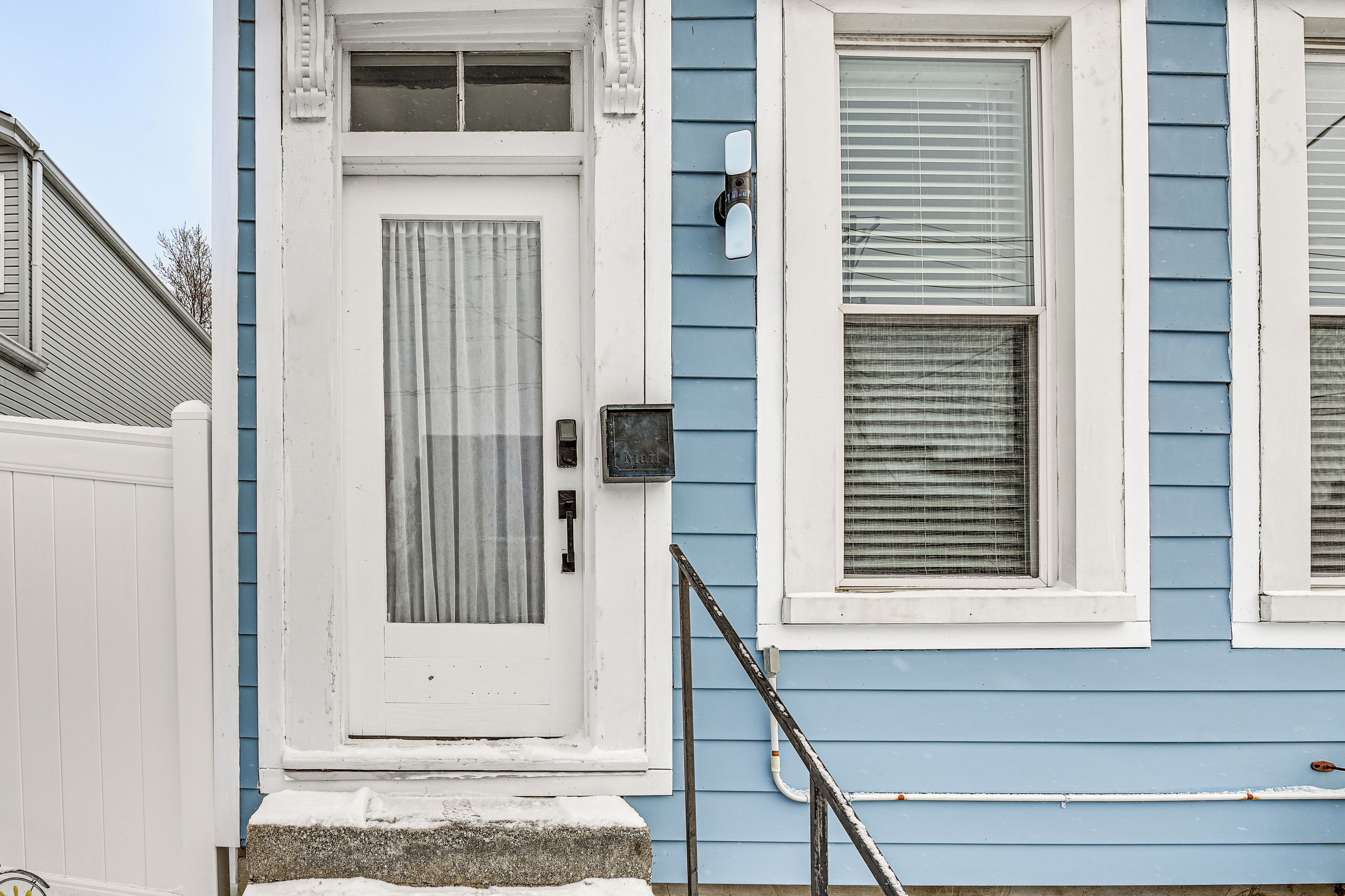 A house with a white front door, a small porch, and a blue siding exterior.