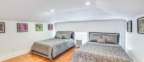 Un dormitorio con dos camas, suelo de madera y cuadros en la pared.