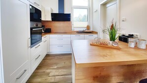 A modern kitchen with white cabinetry, a wooden countertop, and a built-in oven. - Ferienhaus mit Sauna im Ferienpark Mirow (Mirow)