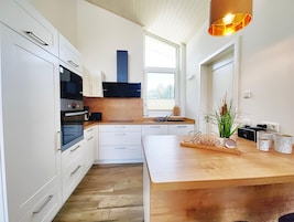 A modern kitchen with white cabinetry, a wooden countertop, and a built-in oven.