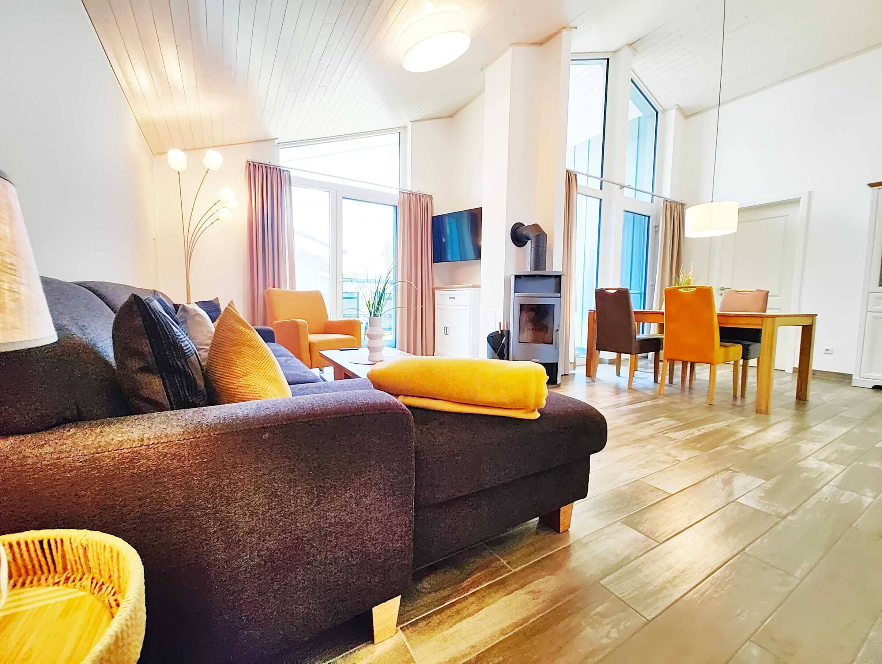 A modern living room with a sofa, chairs, a dining table, and a fireplace.
