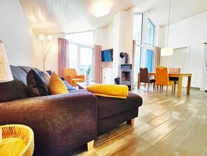 Una sala moderna con un sofá, sillas, una mesa de comedor y una chimenea.