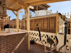A covered outdoor area with a pergola, a metal gate, and exercise equipment.