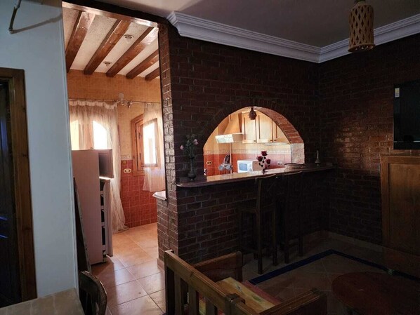 A kitchen with a brick wall, a wooden counter, and a hanging light fixture.