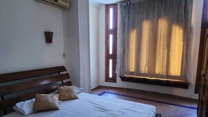 A bedroom with a wooden bed, a window with curtains, and a wall-mounted air conditioner. - Villa Yanny Duplexes Apartment Hurghada El Dahar El Helal (Hurghada)