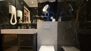 A modern bathroom with a marble vanity, a toilet, and a shower area.