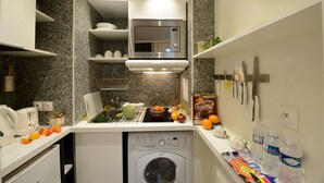 A compact kitchen with a microwave, a dishwasher, and a sink. There are various kitchen items and fresh produce on the counter.