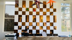 A reception desk with a checkered wall design, a large window, and decorative hanging stars. - The Bay Suite (Brahmagiri)