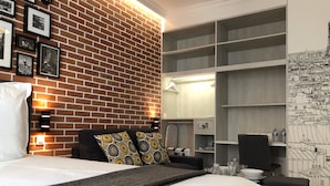 Ein Hotelzimmer mit Backsteinwand, einem Bett mit gemusterten Kissen, einem Schrank mit Regalen und einer Karte an der Wand.