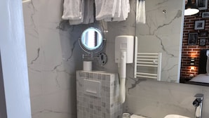Ein Badezimmer mit einem weißen Waschbecken, einem Spiegel, einem Handtuchhalter und einer Toilette.
