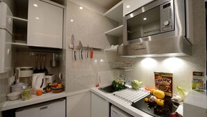 Une cuisine moderne avec des armoires blanches, un four à micro-ondes encastré et un évier.