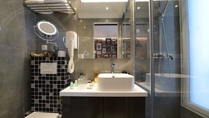 Une salle de bain moderne avec une douche à parois de verre, un lavabo blanc et un mur recouvert de carreaux noirs et blancs.