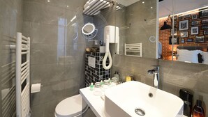 Une salle de bain moderne avec un grand miroir, un lavabo blanc et un porte-serviettes.