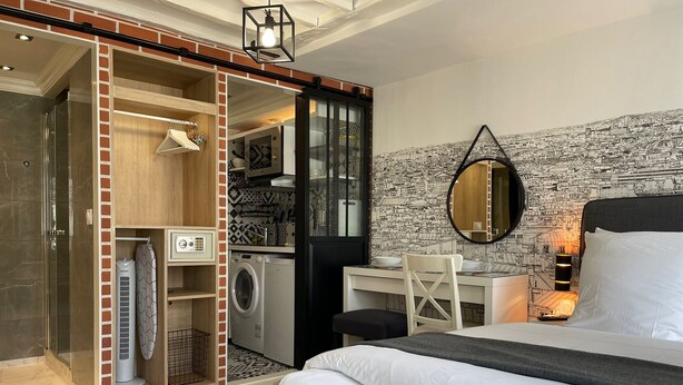Une chambre moderne avec un lit, un bureau et un lave-linge intégré dans un placard.