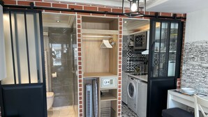 Un espace de vie compact et ouvert, avec une porte coulissante donnant accès à une salle de bain, à un lave-linge et à une petite kitchenette.
