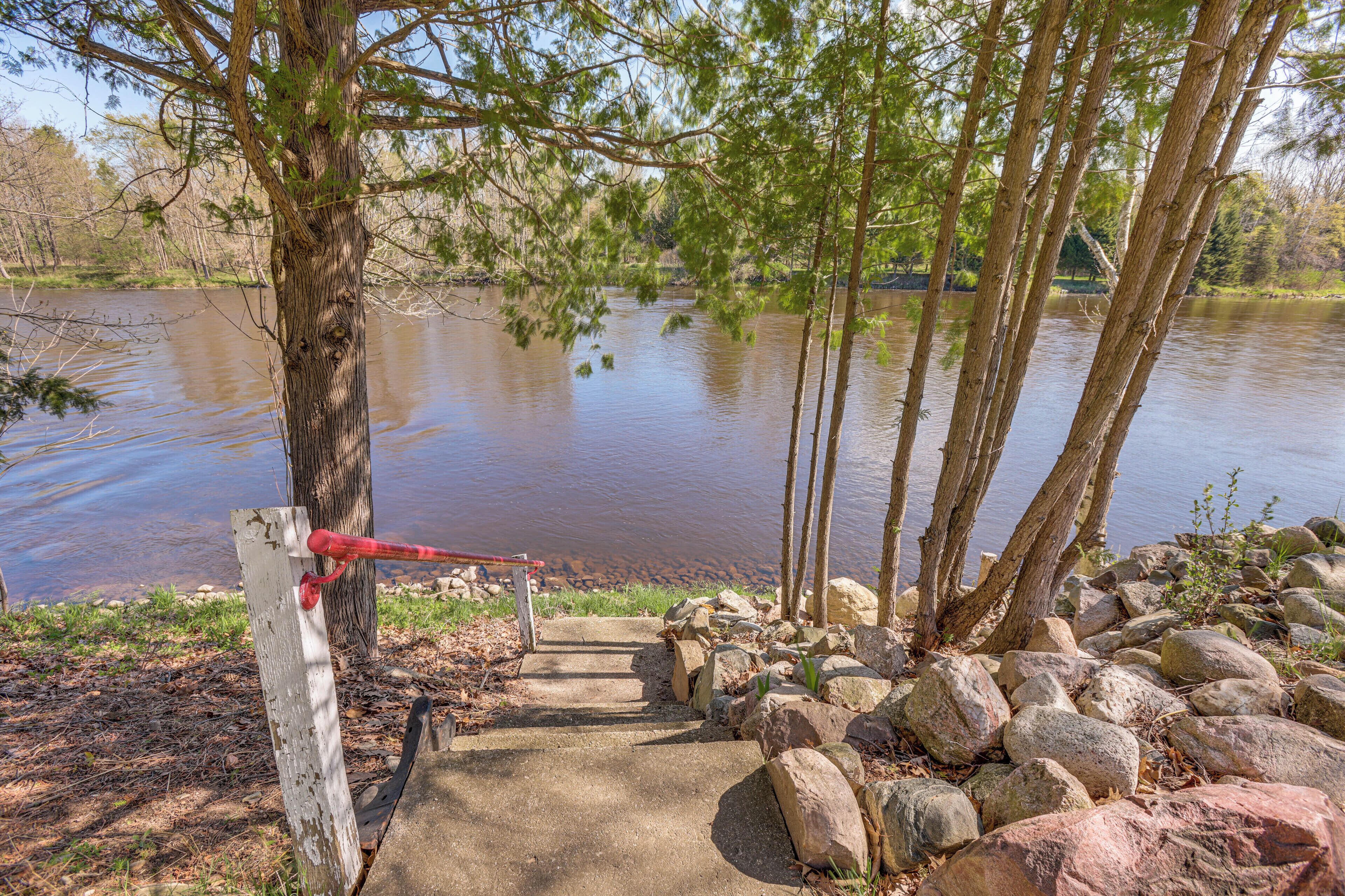 A concrete staircase leading down to a body of water, surrounded by rocks and trees.