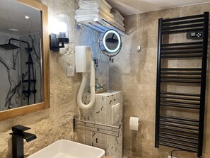 A modern bathroom with a marble-tiled wall, a built-in bathtub, a towel rack, a towel dispenser, and a handheld showerhead. - Loft Jaures (París)