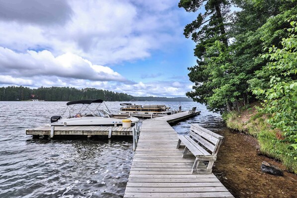 A wooden dock extending into a lake with boats docked at the end.