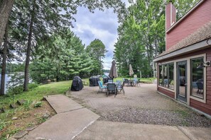 Un espace patio avec des sièges d’extérieur, un barbecue couvert et une vue sur un lac.