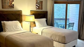A hotel room with two beds, a ceiling light, and a view of the outdoors through a window.