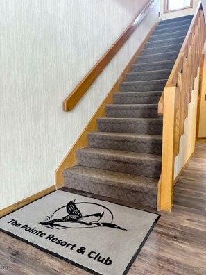 Una escalera con barandillas de madera y peldaños alfombrados que conduce a una plataforma.