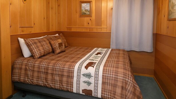 A wooden-paneled room with a bed, a window with a curtain, and a framed picture on the wall. - Old Stoney's Walleye- PET FRIENDLY (Arbor Vitae)