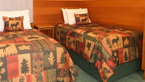Une chambre avec deux lits, des murs en bois et un tableau représentant un cerf.