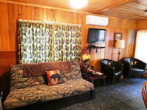 A cozy living room with a patterned sofa, a flat-screen TV, and two leather chairs.
