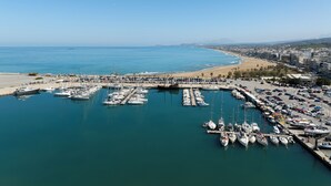 A marina with numerous boats docked, a beach, and a cityscape in the background. - C'est La Vue - Beachfront luxurious condo in Rethymno, Crete (Rethymno)