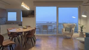 A modern kitchen with a dining area, large sliding glass doors to a balcony, and a view of the sea. - C'est La Vue - Beachfront luxurious condo in Rethymno, Crete (Rethymno)