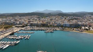 A marina with numerous boats docked, surrounded by a densely populated urban area with buildings and a mountain in the background. - C'est La Vue - Beachfront luxurious condo in Rethymno, Crete (Rethymno)