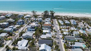 An aerial view of a coastal residential area with houses, a beach, and a clear sky. - The Twins: Your Perfect Budget Beach Getaway! (Anna Maria)