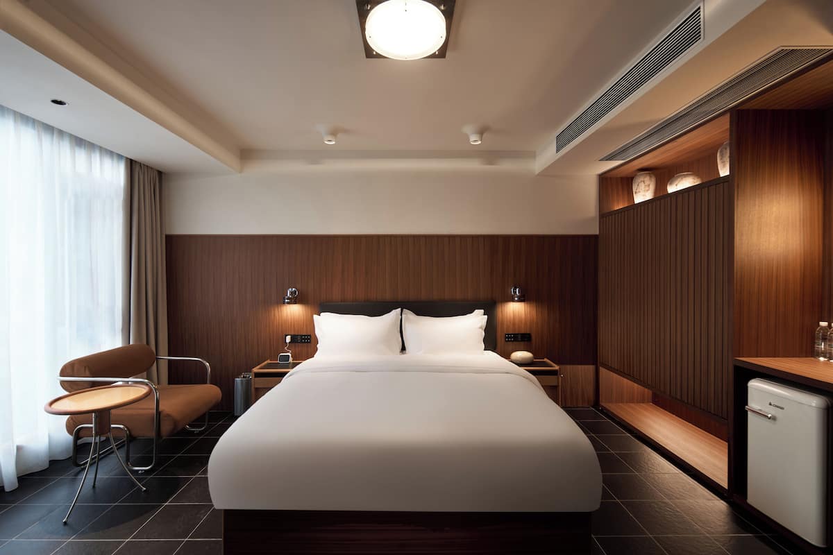 Et moderne hotelværelse med en stor seng, sengeborde, et skrivebord og en stol.