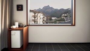 A hotel room with a large window offering a view of mountains and buildings. - The Nest 1219 (Huangshan)