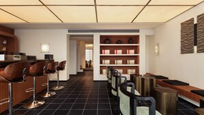 A modern hotel lobby with a reception desk, bar area with stools, and a seating area with benches and chairs. - The Nest 1219 (Huangshan)