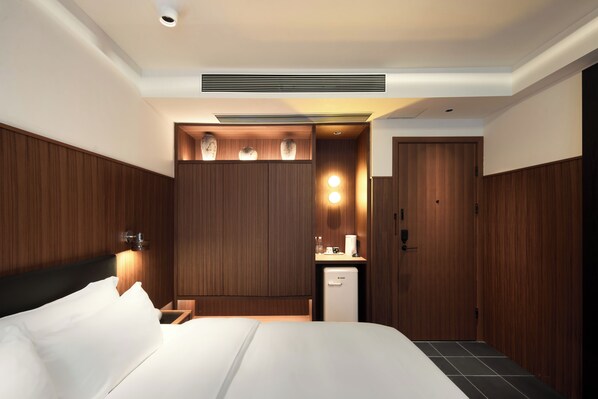 A modern hotel room with a large bed, a small kitchenette, and a wardrobe. - The Nest 1219 (Huangshan)