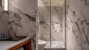 A modern bathroom with a marble wall design, a glass shower enclosure, and a white sink.