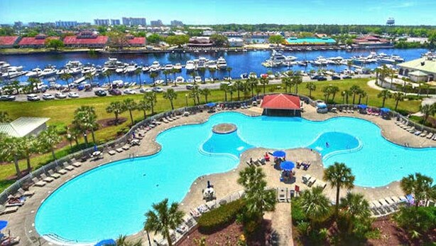 A large, irregularly shaped swimming pool with a central island and surrounding lounge areas. - Barefoot IronWood 1613 Free Shuttle to Pool/Beach (North Myrtle Beach)