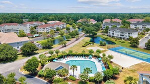 A residential area with multiple apartment buildings, a swimming pool, tennis courts, and a park with a lake. - Barefoot IronWood 1613 Free Shuttle to Pool/Beach (North Myrtle Beach)