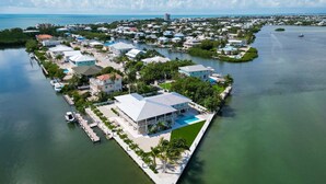 An aerial view of a coastal residential area with houses, a marina, and a large body of water. - Sunset Point | Luxury 5 bdrm w pool, jacuzzi and XL dock, walk to beach (Marathon)