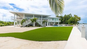 A modern beachfront property with a swimming pool, a covered patio, and a staircase leading to a balcony. - Sunset Point | Luxury 5 bdrm w pool, jacuzzi and XL dock, walk to beach (Marathon)