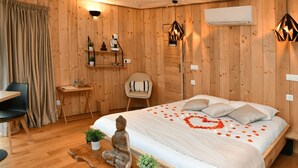 A wooden room with a bed, a desk, a chair, and a small statue.