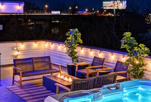 Eine Terrasse im Freien mit Sitzgelegenheit, Feuerstelle und Whirlpool.