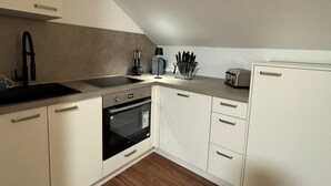 A modern kitchen with white cabinets, a stainless steel sink, a built-in oven, and a refrigerator. - City Oasis - Central vacation apartment (Nürnberg)