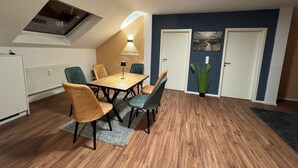 A dining area with a wooden table and chairs, a ceiling light, and a radiator. - City Oasis - Central vacation apartment (Nürnberg)