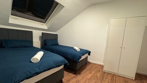A bedroom with two beds, a wardrobe, and a window. - City Oasis - Central vacation apartment (Nürnberg)